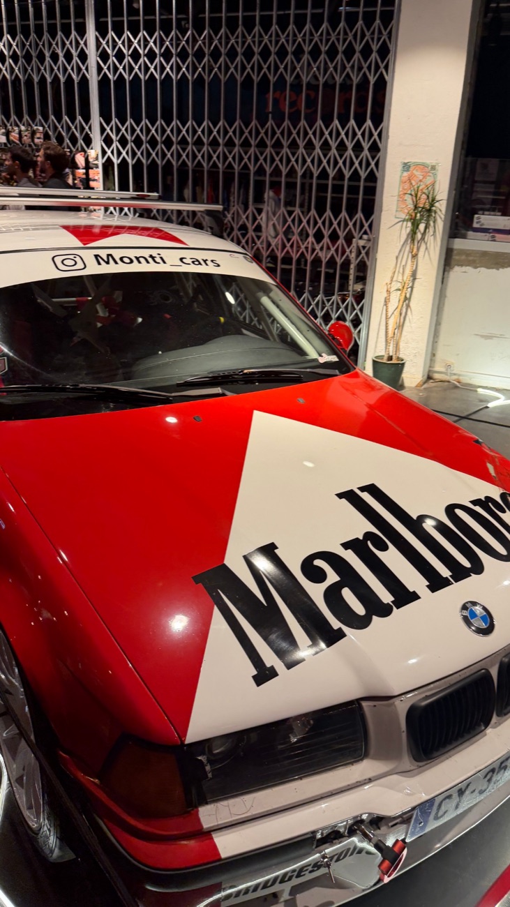 Voiture de course aux couleurs rouge et blanc, capot à chevron et grand lettrage noir